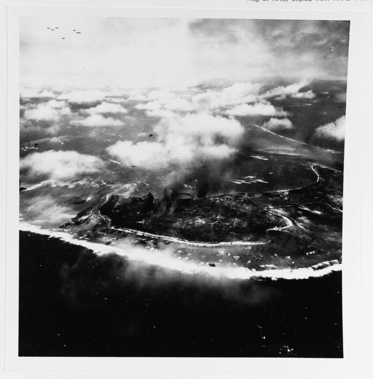 Assault landing craft approach Namur (center) and Roi (right) Islands, Kwajalein Atoll, during landings on them, 1 February 1944. Note devastation on Namur Island, with smoke still rising from bombardment. A flock of TBM bombers is in the upper left, and a single OS2U is in lower center. Photographed by a USS SUWANEE (CVE-27) plane. Naval History and Heritage Command Photo.