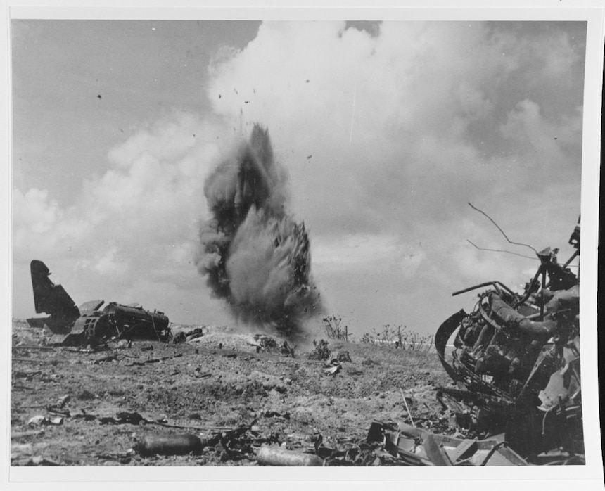 Marine demolition men blowing up a Japanese dugout, while clearing snoopers on Roi Island, Kwajalein Atoll, 1 February 1944. Note wrecked Japanese G4M ("Betty") bomber and fuel truck at left. Naval History and Heritage Command Photo.
