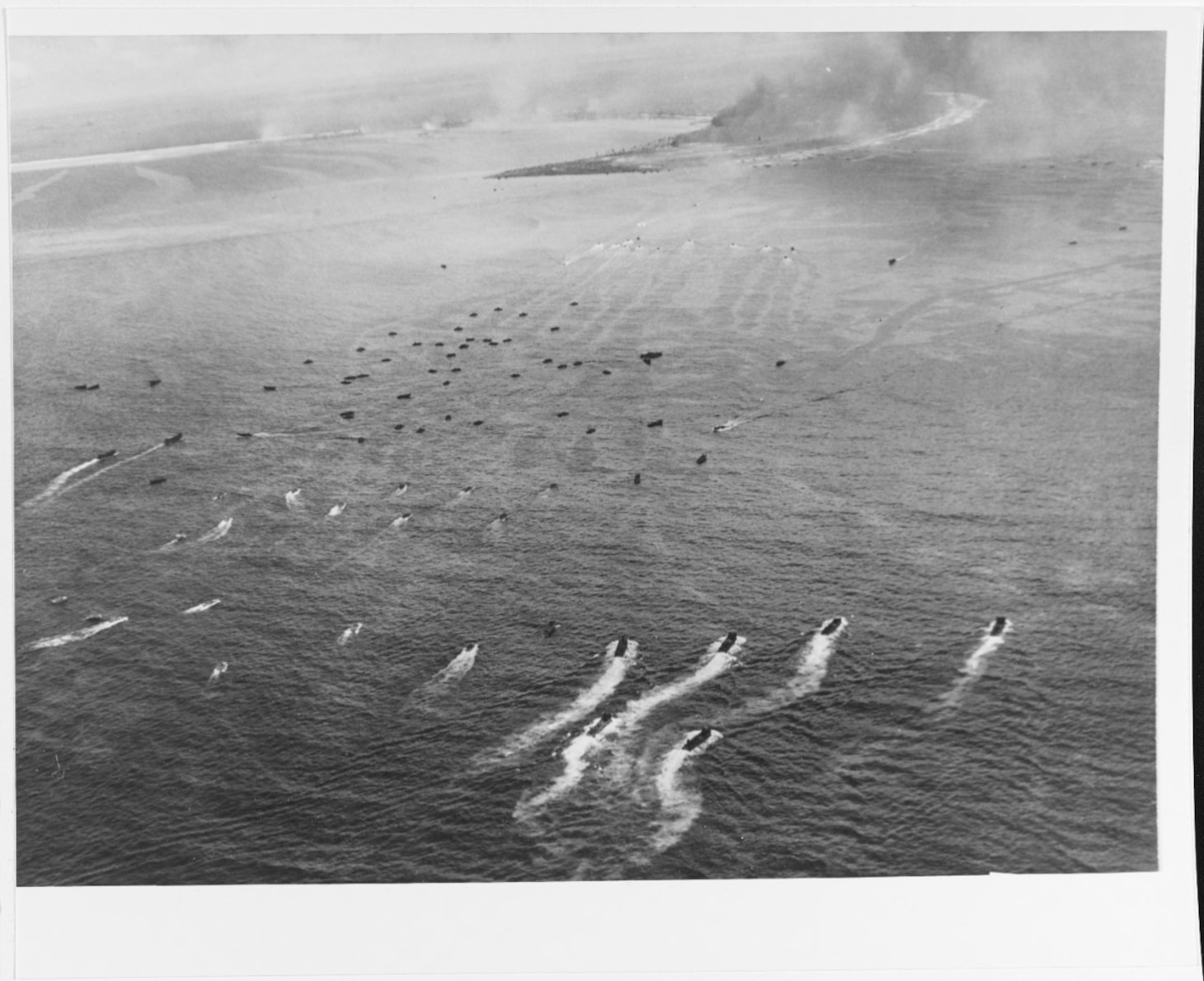 Landing craft move toward Kwajalein Island's western end, during resupply operations on "D+2" day, 3 February 1944. Boats in foreground are LCMS. Most others are LVT amphibious tractors. Photographed from a USS CORAL SEA (CVE-57) plane. Naval History and Heritage Command Photo.