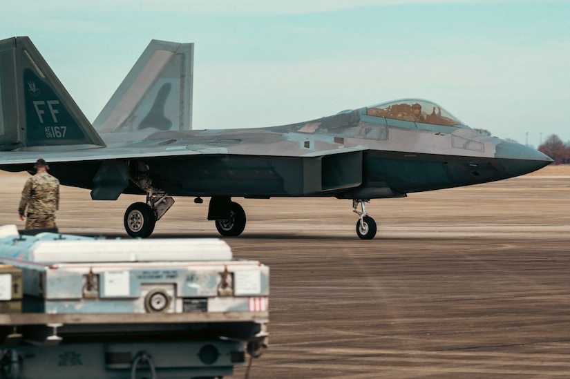 An F-22 Raptor prepares to be resupplied during the Tactics Advancement Course at Joint Base Langley-Eustis, Va., Feb. 7, 2024. Airmen assigned to the 6th Airlift Squadron loaded cargo onto the C-17 Globemaster III in order to provide support for the F-22s at JBLE. The advancements course postures Air Mobility Command Airmen to execute agile operations on a global scale. (U.S. Air Force photo by Airman 1st Class Ian Sullens)