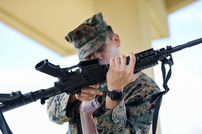 U.S. Marine Corps Cpl. Tylerruben Salas, small arms repair technician for Marine Corps Base Camp Blaz, conducts rifle, pre-fire inspections before shooting on Marine Corps Base Camp Blaz, Guam, Sept. 25, 2023. The Marine Corps’ Program Manager for Training Systems will conduct target calibration from Sept. 25 to Oct. 27 and testing from Dec. 4-15.  Two of four ranges at the Live Fire Training Range Complex will be equipped with new technology that provide more efficient and effective combat marksmanship training to support combat readiness. The live-fire location of miss and hit or LOMAH technology, replaces the human element of observing and marking targets. The calibration and testing are to ensure that the LOMAH system is working properly. (U.S. Marine Corps photo by Lance Cpl. Garrett Gillespie)