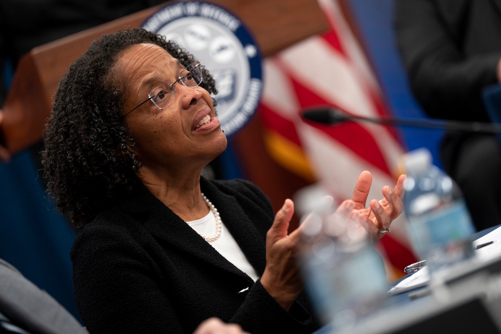 A civilian sits at a table making hand gestures.