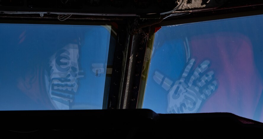 The 23rd Bomb Squadron flag reflects off of the windshield of a B-52H Stratofortress over the Pacific Ocean, Feb. 12, 2024. The mission of the "Bomber Barons" is to fly the B-52H Stratofortress, projecting global power. (U.S. Air Force photo by Airman 1st Class Alyssa Bankston)
