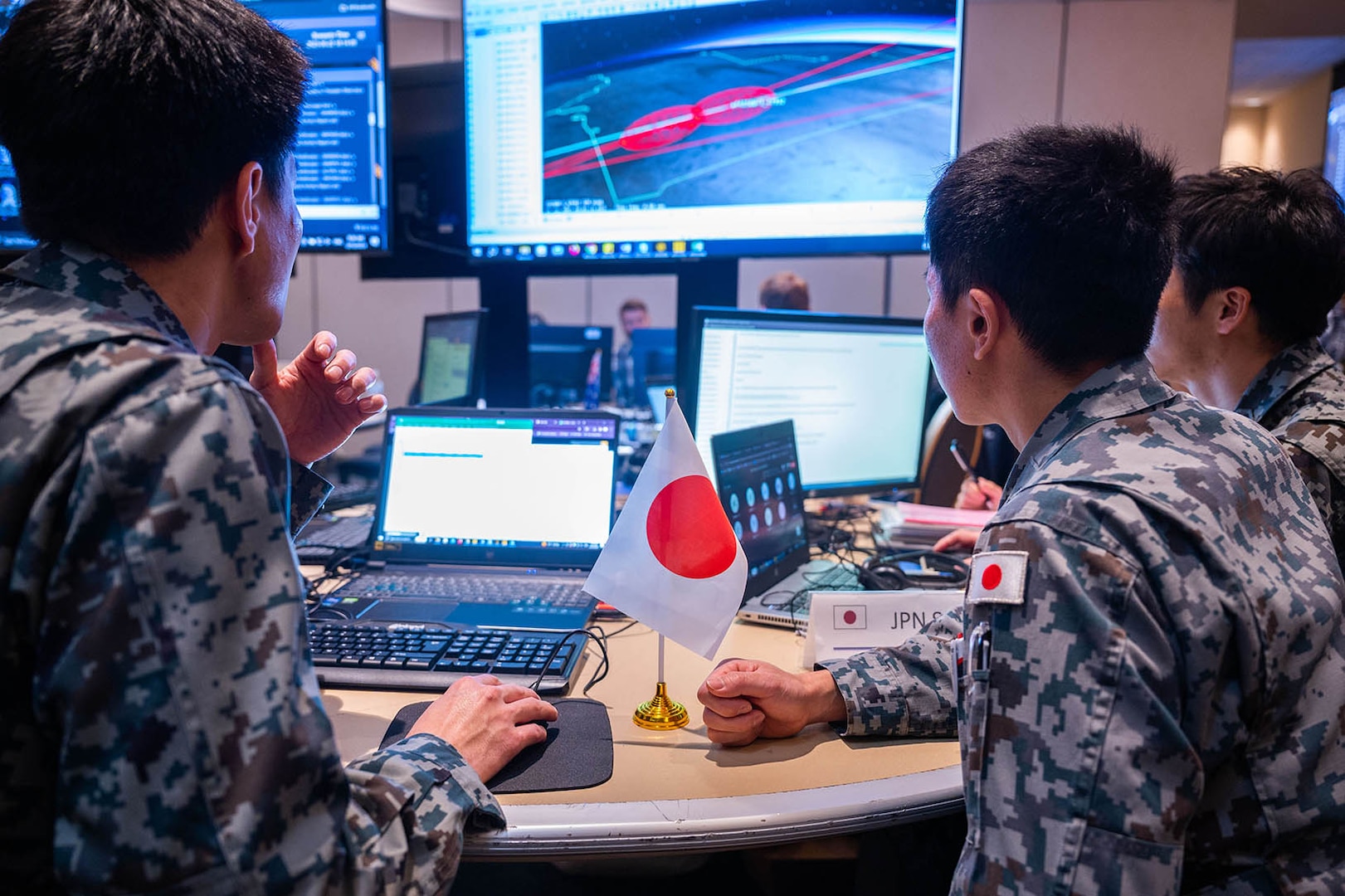 Members of a foreign military observe a computer display.