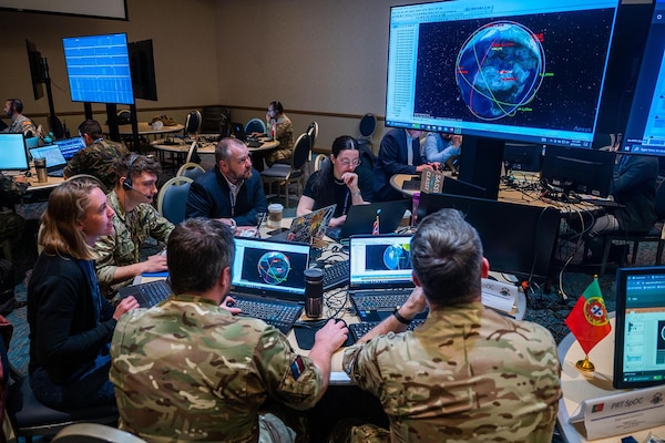 Members of a foreign military and civilians observe a computer display.