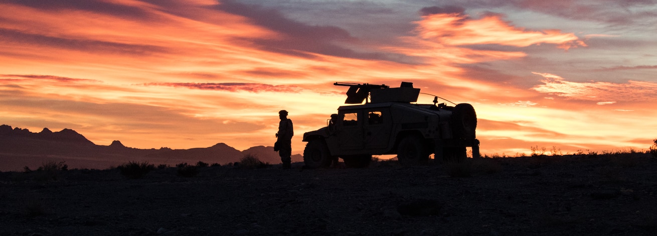 Oklahoma National Guard banner ad for Holistic Health and Fitness. The image features an armored humvee silhouetted against an orange sunset. 