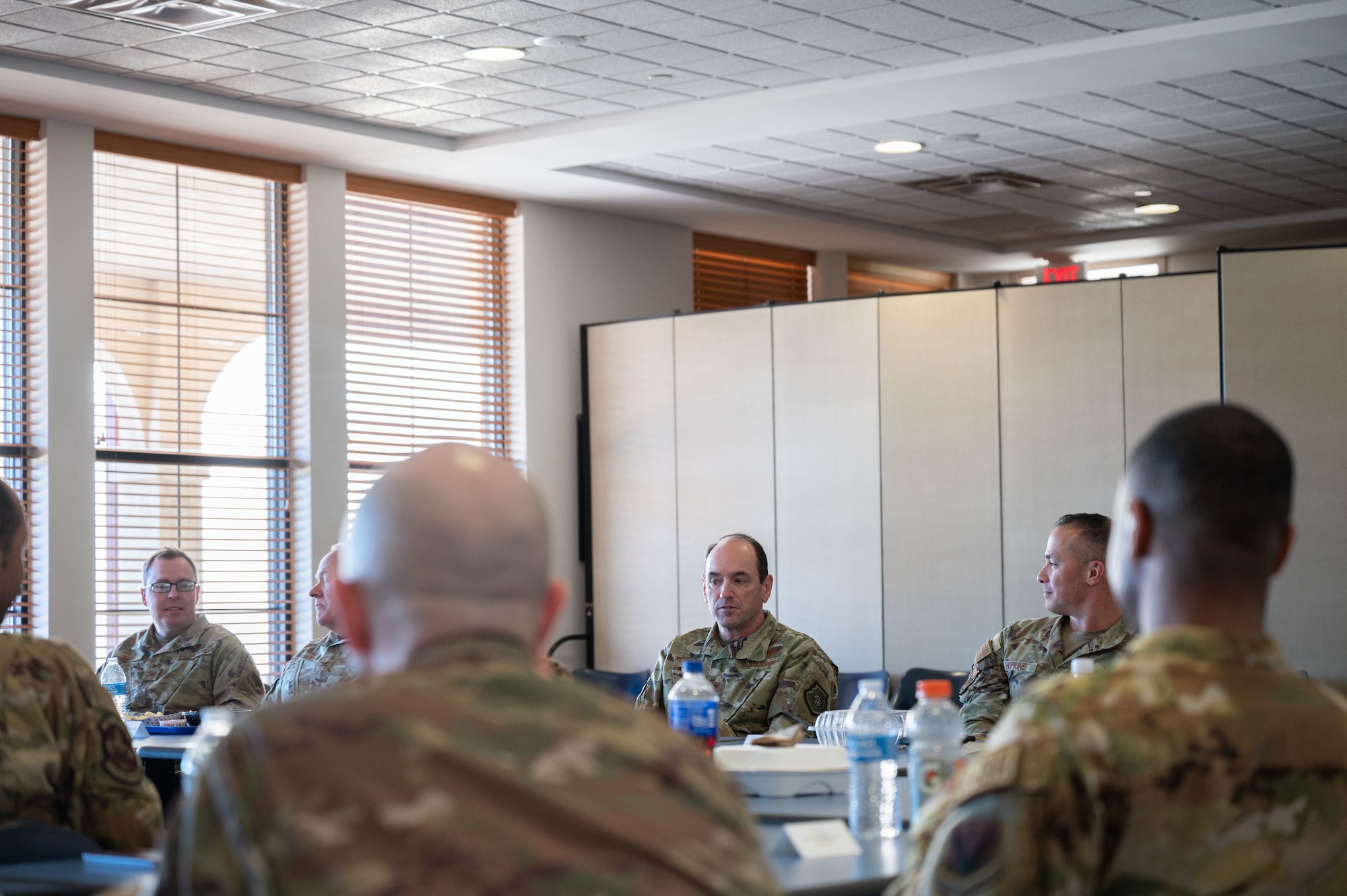 A group of men in military uniform sit around a conference table.