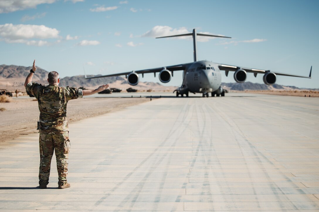U.S. Air Force Maj. Richard Elliot, a Fayetteville, North Carolina native, instructor pilot with the 14th Airlift Squadron, 437th Airlift Wing, directs a C-17 Globemaster III during a strategic mobility exercise as part of Service Level Training Exercise 2-24 at Camp Wilson, Marine Corps Air-Ground Combat Center, Twentynine Palms, California, Jan. 25, 2024. Joint interoperability between the Air Force and the U.S.
Marine Corps enables Marine units to rapidly embark on C-17’s, allowing the Marine Corps to provide support for expeditionary operations. (U.S. Marine Corps photo by Lance Cpl. Richard PerezGarcia)