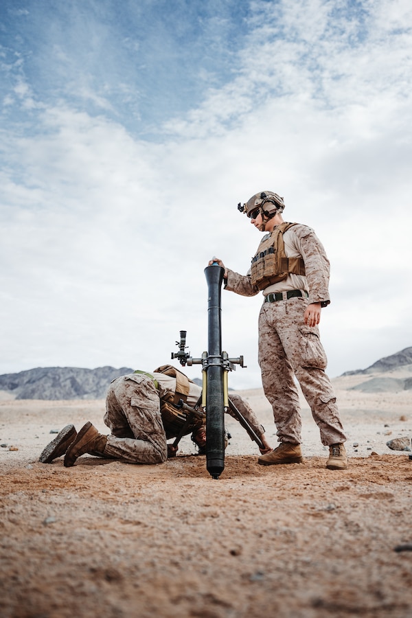 U.S. Marine Corps Lance Cpl. Serjio Cecena, a Phoenix, Arizona native, left, and Lance Cpl. Lawson Hebert, a Kankakee, Illinois native, both mortarmen with 2nd Battalion, 4th Marine Regiment, 1st Marine Division, prepare to fire an 81 mm mortar round during an Integrated Training Exercise as part of Service Level Training Exercise 2-24 at Range 106A, Marine Corps Air-Ground Combat Center, Twentynine Palms, California, Jan. 20, 2024. The purpose of ITX is to create a challenging, realistic, training environment that produces combat-ready forces capable of operating as an integrated Marine Air-Ground Task Force and to prepare units for their role in the MAGTF Warfighting Exercise. (U.S. Marine Corps photo by Lance Cpl. Richard PerezGarcia)