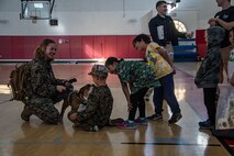 U.S. Marine Corps Lance Cpl. Sarah Grawcock, a combat photographer and mascot handler with Headquarters and Service Battalion, and Pfc. Bruno, the Marine Corps Recruit Depot San Diego and Western Recruiting Region mascot, interact with participants of the "In Their Boots" and "Devil Pups"  events at MCRD San Diego on Feb. 16, 2024. The Devil Pups event is aimed at providing children ages 5-12 with engaging activities that introduce them to aspects of the Marine Corps lifestyle, fostering learning and discipline in a fun environment. (U.S. Marine Corps photo by Sgt. Jesse K. Carter-Powell)