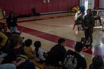 U.S. Marine Corps Lance Cpl. Sarah Grawcock, a combat photographer and mascot handler with Headquarters and Service Battalion, and Pfc. Bruno, the Marine Corps Recruit Depot San Diego and Western Recruiting Region mascot, interact with participants of the "In Their Boots" and "Devil Pups" events at MCRD San Diego on Feb. 16, 2024. The Devil Pups event is aimed at providing children ages 5-12 with engaging activities that introduce them to aspects of the Marine Corps lifestyle, fostering learning and discipline in a fun environment. (U.S. Marine Corps photo by Sgt. Jesse K. Carter-Powell)