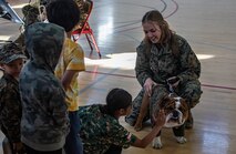 U.S. Marine Corps Lance Cpl. Sarah Grawcock, a combat photographer and mascot handler with Headquarters and Service Battalion, and Pfc. Bruno, the Marine Corps Recruit Depot San Diego and Western Recruiting Region mascot, interact with participants of the "In Their Boots" and "Devil Pups"  events at MCRD San Diego on Feb. 16, 2024. The Devil Pups event is aimed at providing children ages 5-12 with engaging activities that introduce them to aspects of the Marine Corps lifestyle, fostering learning and discipline in a fun environment. (U.S. Marine Corps photo by Sgt. Jesse K. Carter-Powell)