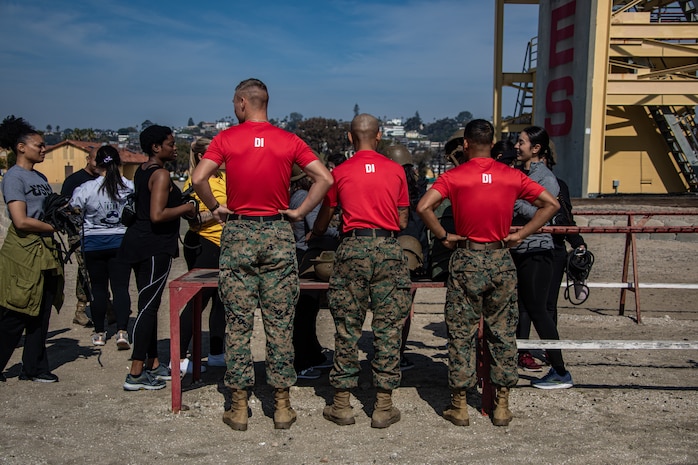 U.S. Marine Corps Sgt. Payton Bauserman (left), Sgt. Harry Le (center), and Melvin Melendezgarcia (right), all Drill Instructors with 1st Recruit Training Battalion, Recruit Training Regiment, hand out gear for the rappel tower to the spouses taking part in the "In Their Boots" event at Marine Corps Recruit Depot San Diego, Feb. 16, 2024. In Their Boots is designed to inform Marine Corps spouses about the duties of their significant others and give them a peek into the rigors of recruit training. (U.S. Marine Corps photo by Sgt. Jesse K. Carter-Powell)