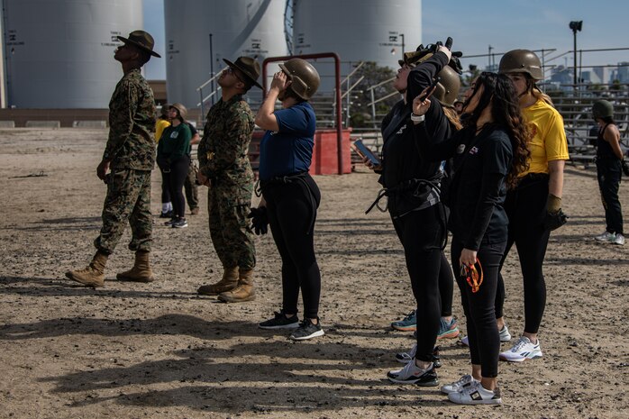 U.S. Marine Corps spouses taking part in the "In Their Boots" event observe fellow participants at the rappel tower on Marine Corps Recruit Depot San Diego, Feb. 16, 2024. In Their Boots is designed to inform Marine Corps spouses about the duties of their significant others and give them a peek into the rigors of recruit training. (U.S. Marine Corps photo by Sgt. Jesse K. Carter-Powell)