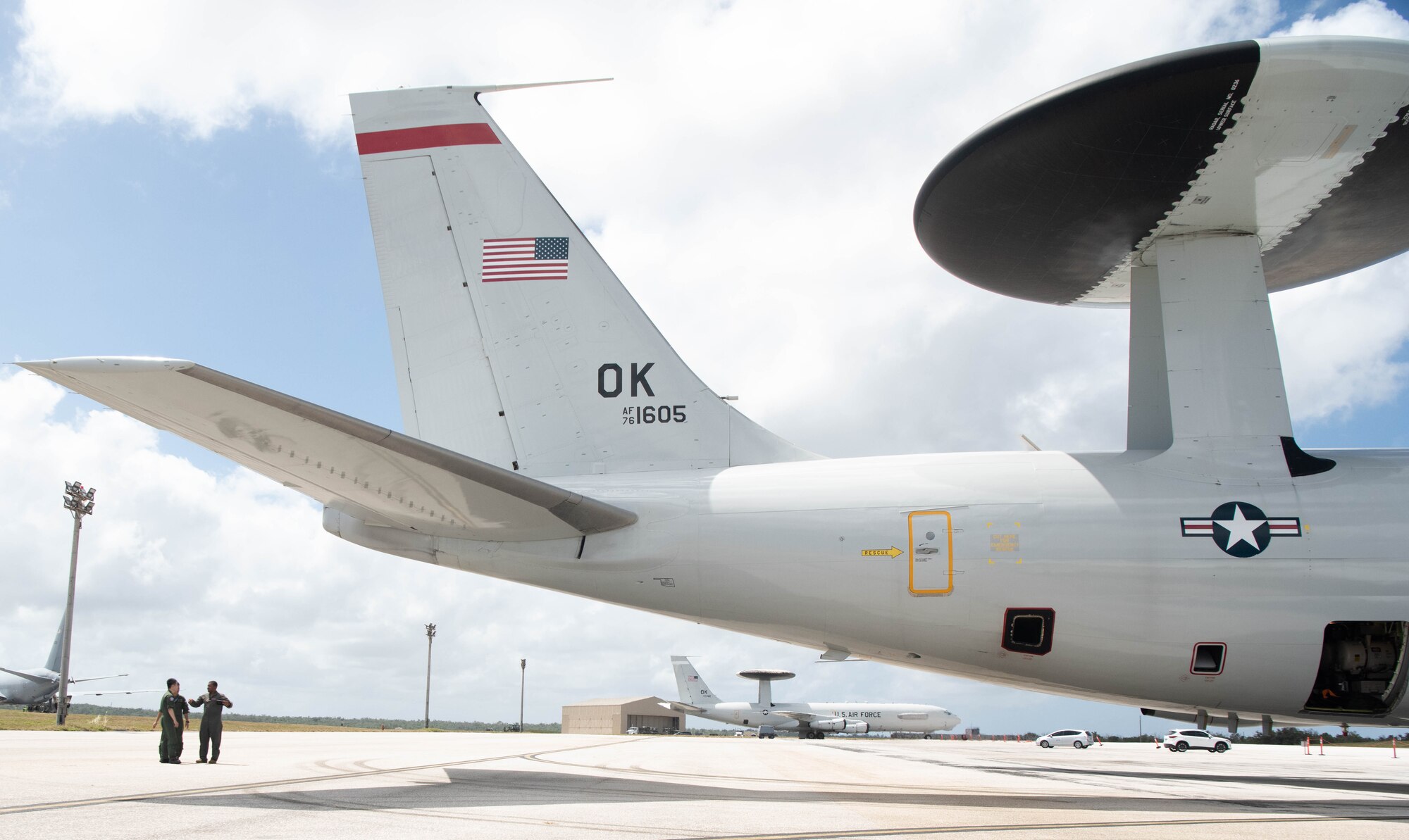 Airmen look at the tail of an aircraft.