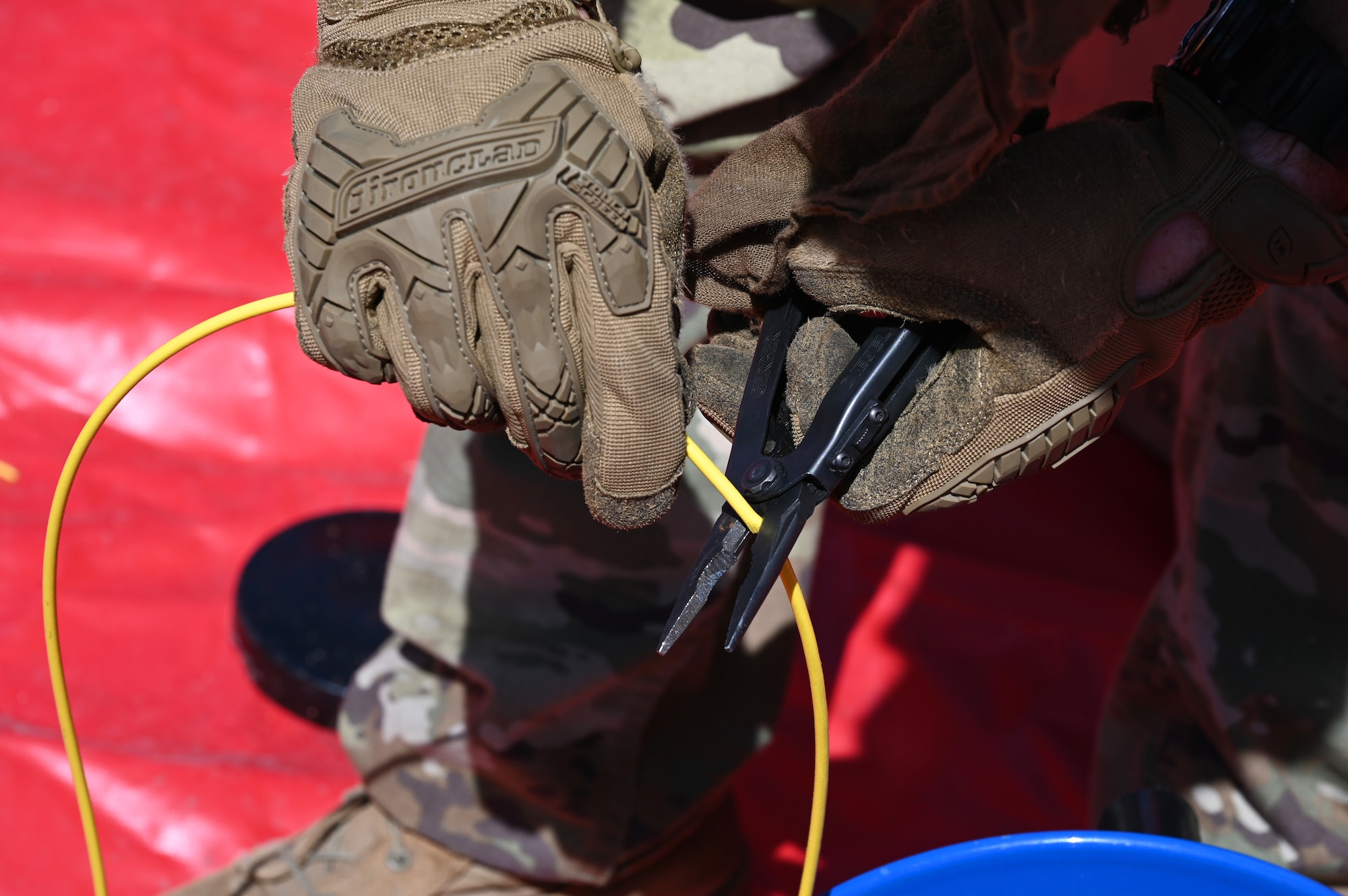 An Airman uses a cutter to cut a wire.