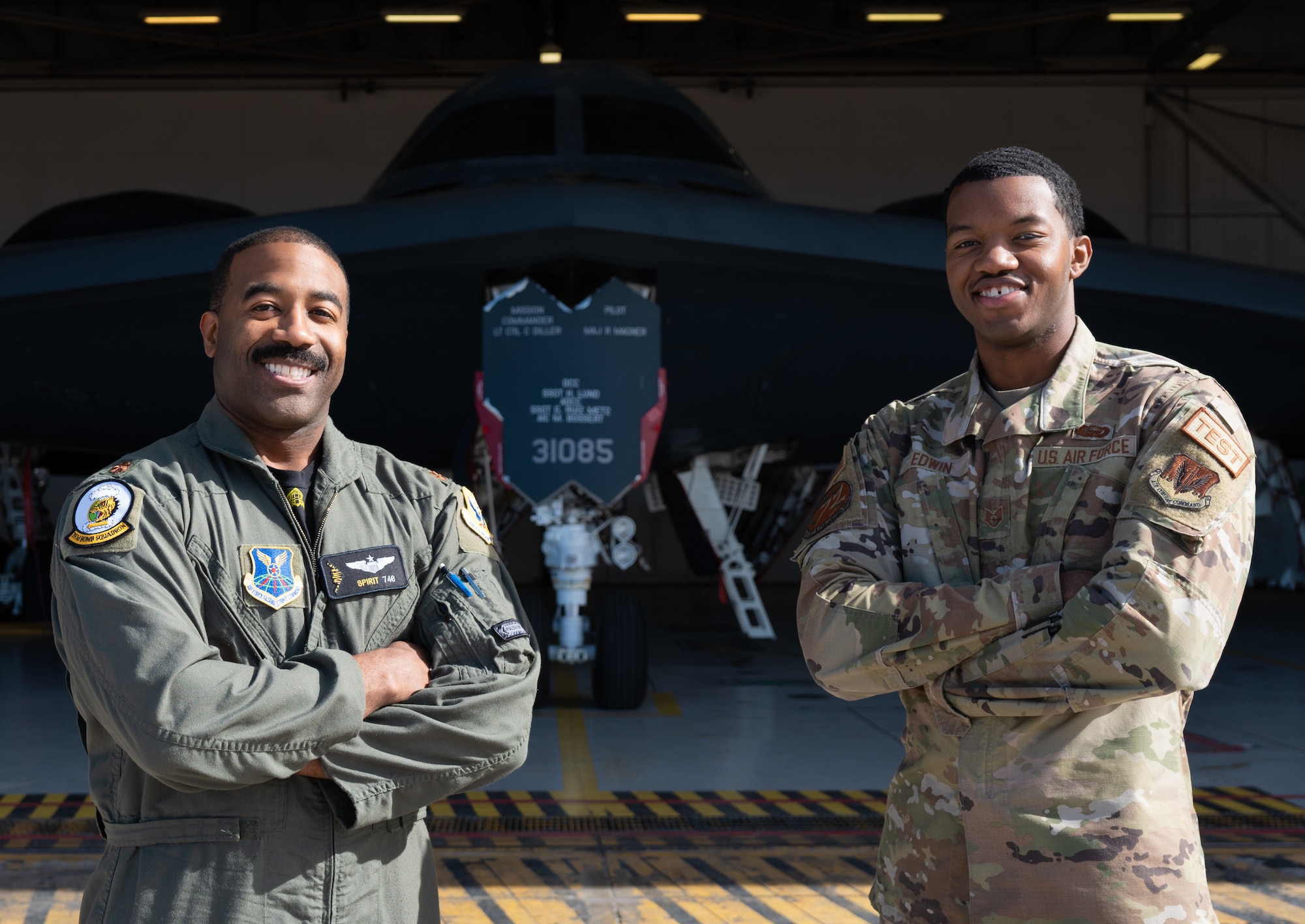 U.S. Air force Major Alfred Agee, 393rd Bomb Squadron assistant director of operations, left, and Staff Sgt. Raphael Edwin, 72nd Test and Evaluation Squadron non-commissioned officer in charge of commander support staff, right, pose in front of a B-2 Spirit stealth bomber at Whiteman Air Force Base, Missouri, Feb 9, 2024. The picture was taken for Black History Month and showing off the current and future pilots of the B-2. (U.S. Air Force photo taken by Senior Airman Joseph Garcia)