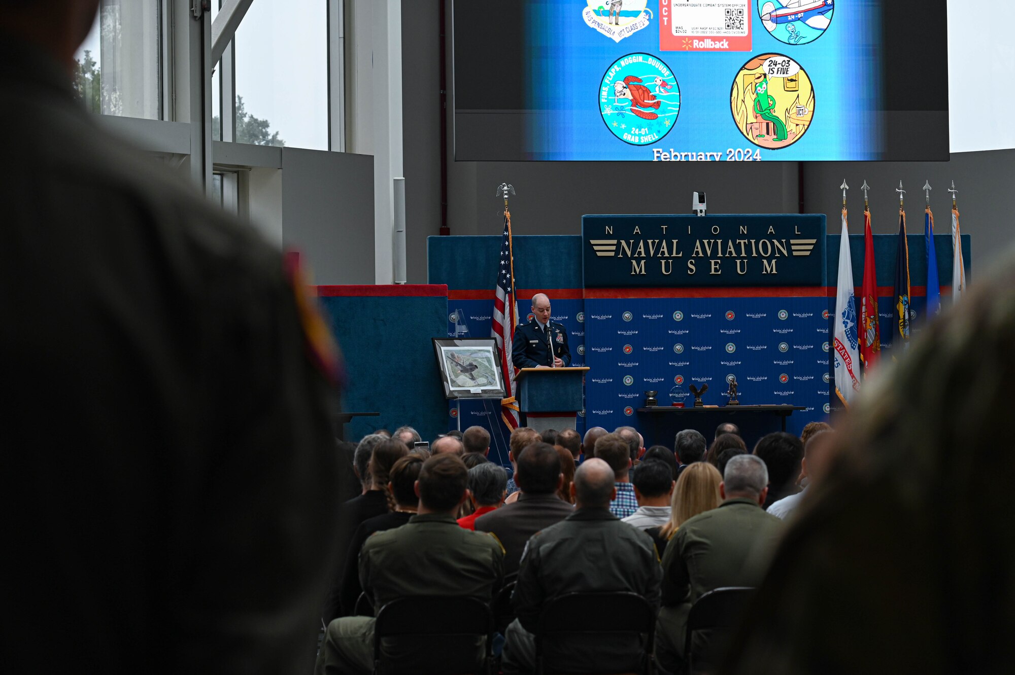 U.S. Air Force Col. John Christianson, 350th Spectrum Warfare Wing deputy commander, gives the keynote address during the Undergraduate Combat Systems Officers Course graduation ceremony at the National Naval Aviation Museum, Naval Air Station Pensacola, Fla., Feb. 16, 2024. 21 students graduated from the course and have been matched to follow-on stations to learn how to operate on their assigned aircraft as CSOs for the Air Force. (U.S. Air Force photo by Capt. Benjamin Aronson)