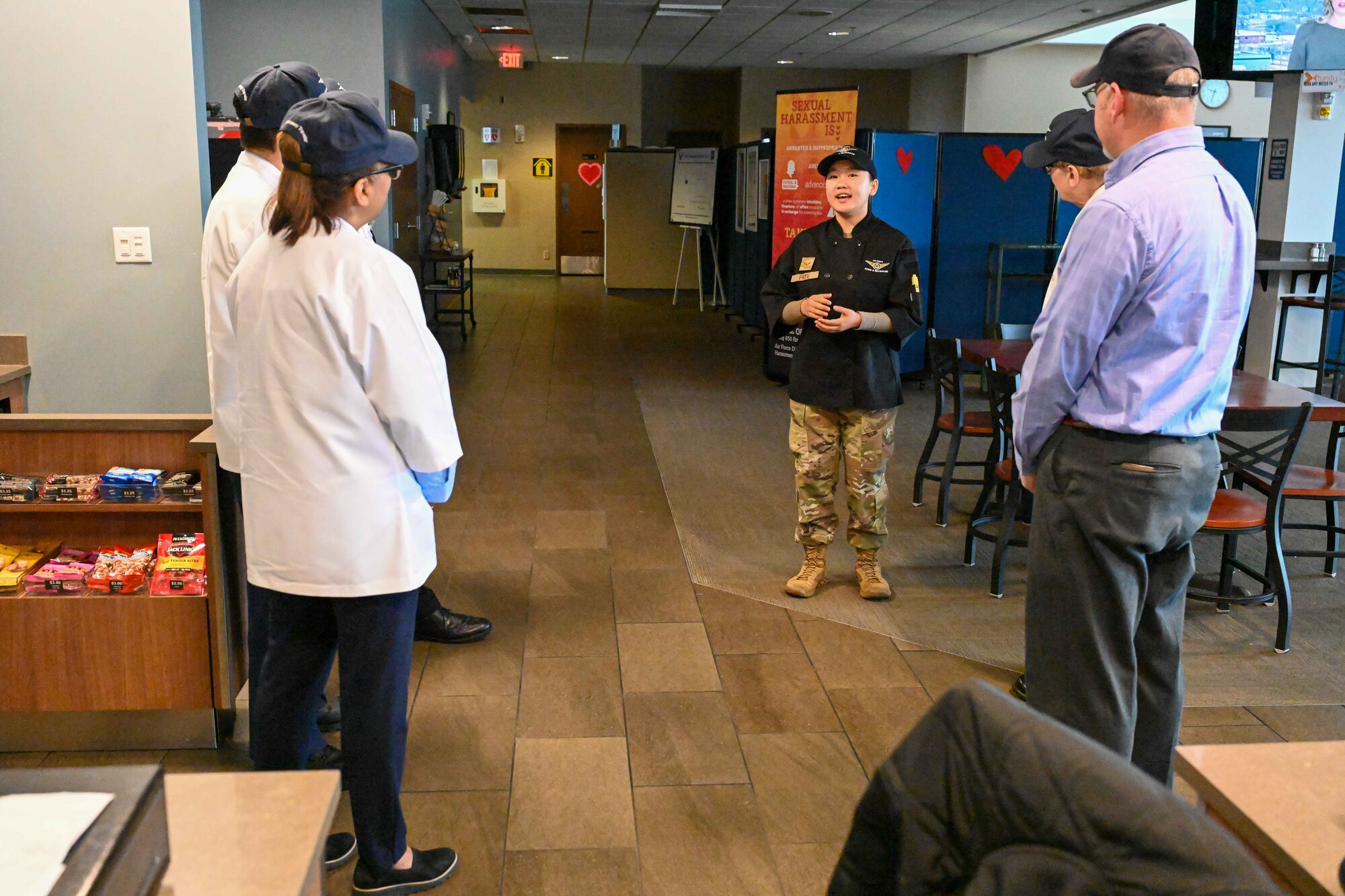 Airman 1st Class Saw Lournne Phyu, 22nd Force Support Squadron food service apprentice, talks to the Hennessy Award critics at McConnell Air Force Base, Kansas, Feb. 15, 2024. The Hennessy Award is an annual recognition given to the base with the best dining facility in the Air Force. (U.S. Air Force photo by Airman 1st Class William Lunn)