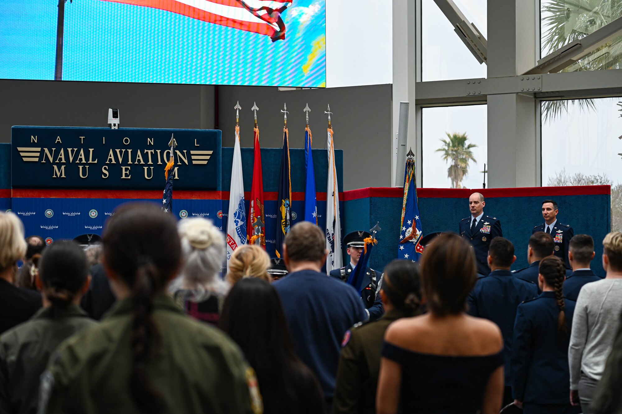 U.S. Air Force Col. John Christianson, 350th Spectrum Warfare Wing deputy commander, left, and U.S. Air Force Col. Shane Muscato, 479th FTG commander, right, stand at attention during the National Anthem at the Undergraduate Combat Systems Officers Course graduation ceremony at the National Naval Aviation Museum, Naval Air Station Pensacola, Fla., Feb. 16, 2024. 21 students graduated from the course and have been matched to follow-on stations to learn how to operate on their assigned aircraft as CSOs for the Air Force. (U.S. Air Force photo by Capt. Benjamin Aronson)
