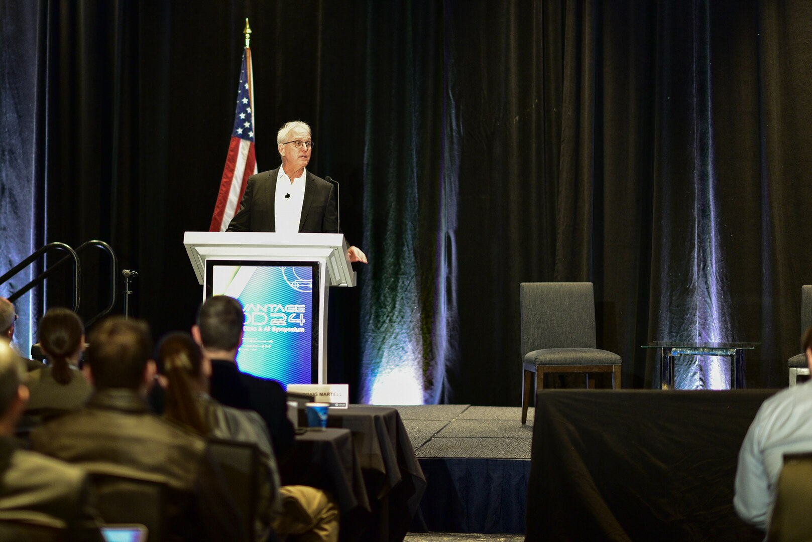 A person in a business suit stands at a lectern.