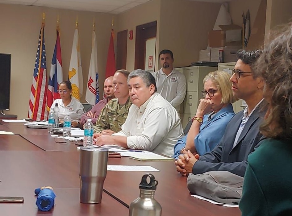 Group of people at a conference table with US, Puerto Rico and USACE flags in the background.