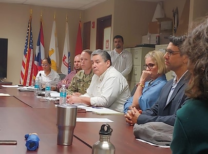Group of people at a conference table with US, Puerto Rico and USACE flags in the background.