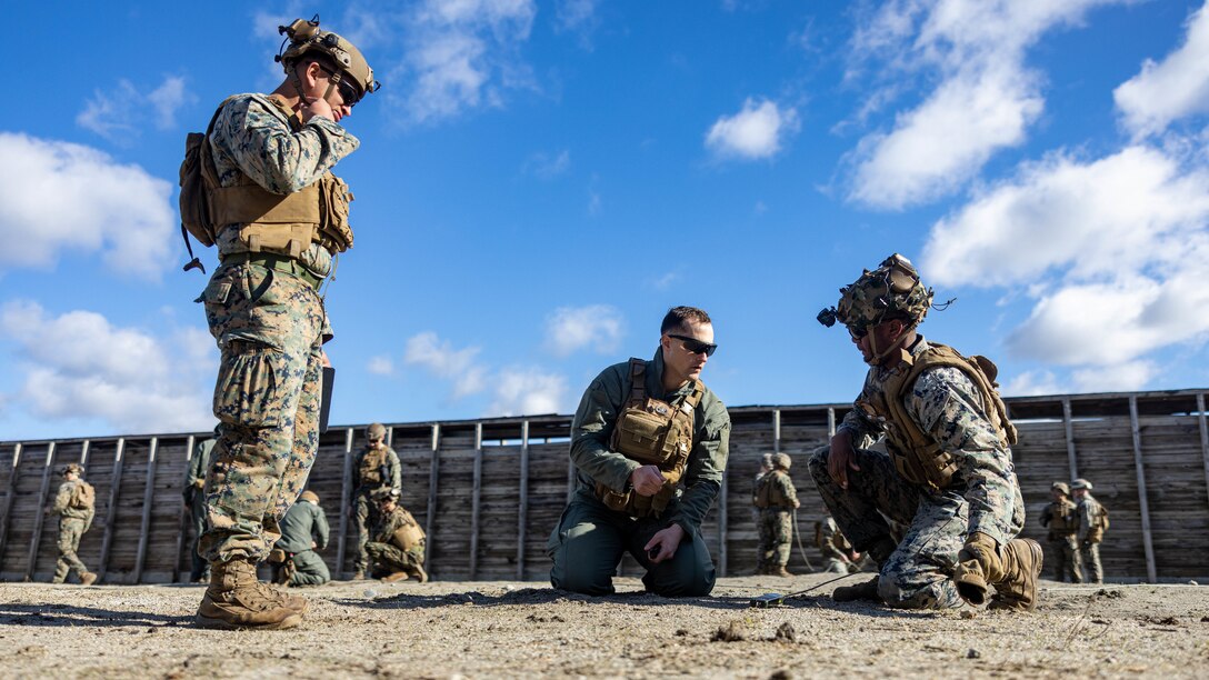 U.S. Marine Corps Sgt. Mitchel Swafford, center, an explosive ordnance disposal technician with 8th Engineer Support Battalion, Combat Logistics Regiment 27, 2nd Marine Logistics Group, instructs Cpl. Jayden Johnson, right, and Lance Cpl. Ryan Bell, both riflemen with 3rd Battalion, 2nd Marine Regiment, 2nd Marine Division, on how to conduct proper procedures during a basic demolition range on Camp Lejeune, North Carolina, Feb. 13, 2024. The training exposed 2nd MLG and 2nd Marine Division Marines to the EOD program, enhancing their baseline understanding of EOD and generate interest as potential lateral move candidates . (U.S. Marine Corps photo by Cpl. Alfonso Livrieri)