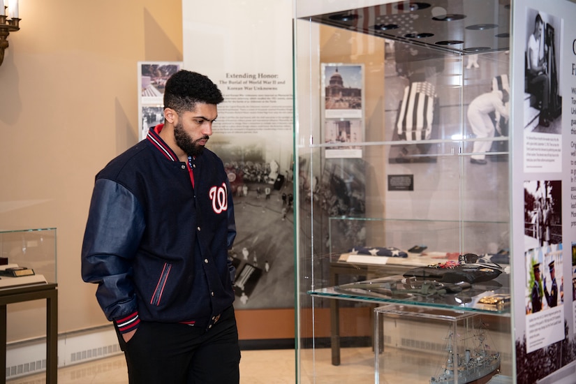 A person wearing a Washington Nationals jacket looks at a display case containing artifacts.