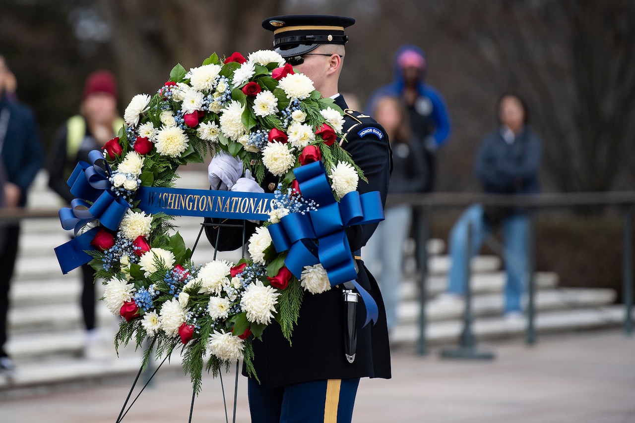 A soldier carries a wreath.