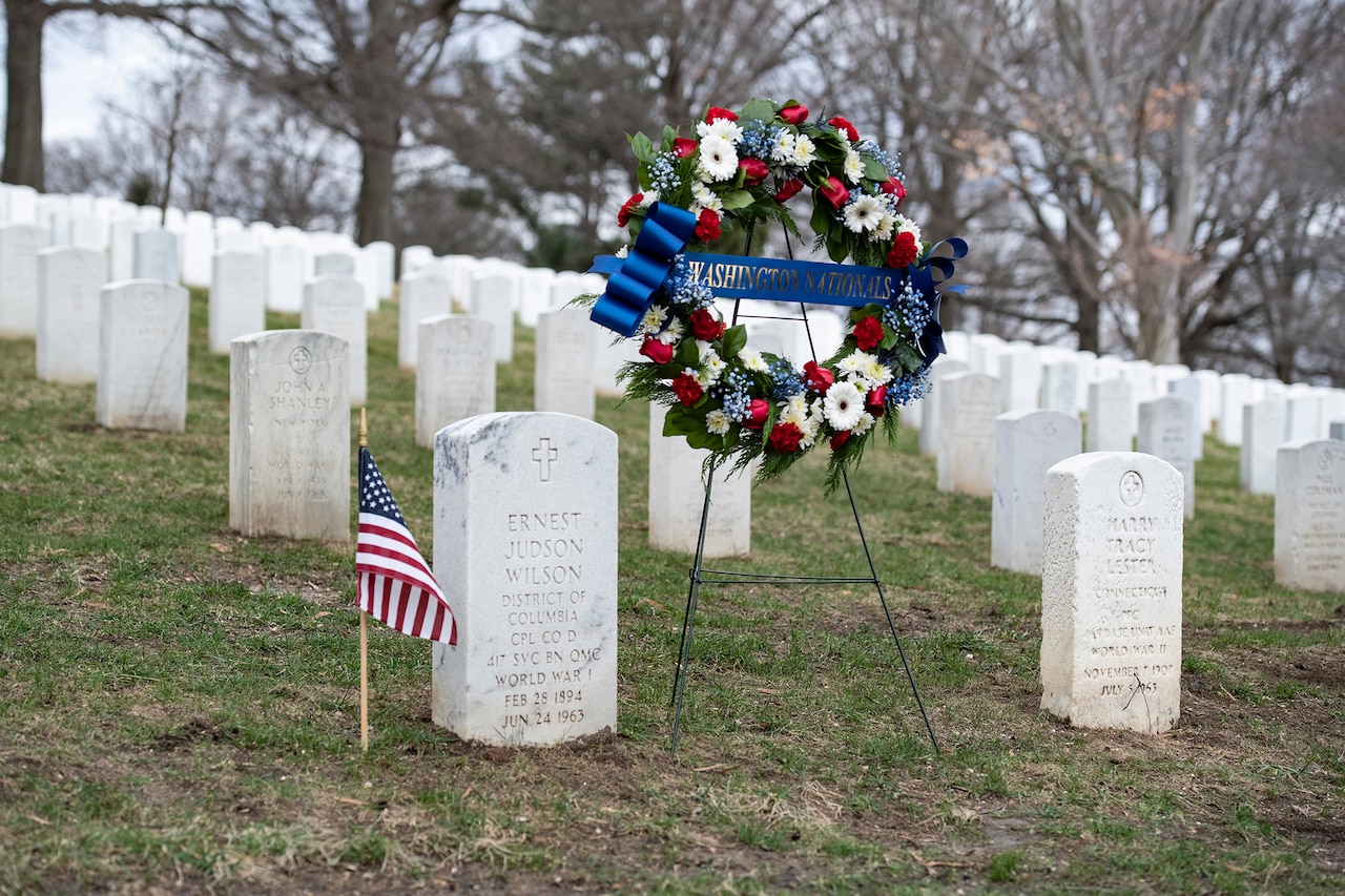 A wreath and American flag flank a military grave.