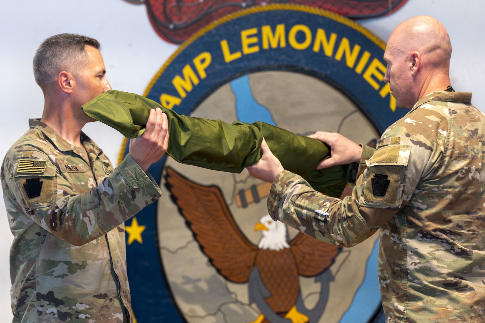 U.S. Army Lt. Col. Erik Ponzek, left, commander of 2-112th Infantry, and Command Sgt. Maj. Jason Barclay, 2-112th Infantry senior enlisted leader, unfurl their unit's colors during a transfer of authority ceremony at Camp Lemonnier, Djibouti, Feb. 10, 2024. This act represented Pennsylvania National Guard's Task Force Paxton assuming control over the SECFOR unit in CJTF-HOA.