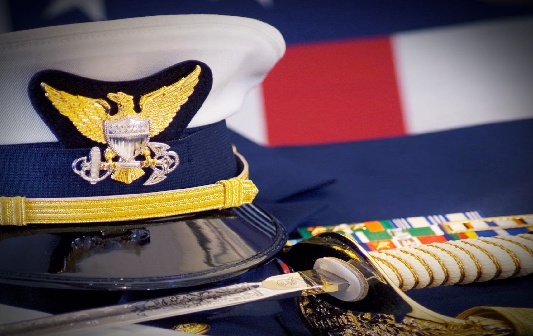 A Coast Guard Officer's hat, sword, gloves and ribbons are displayed together with the American Flag. (U.S. Coast Guard photo)