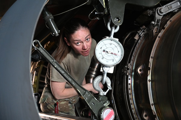 An airman looks up from engine housing.