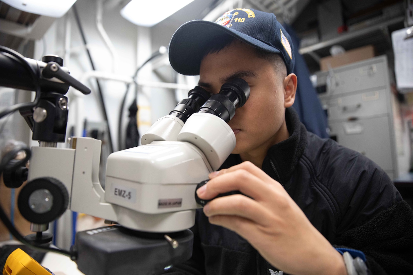 A sailor looks into a microscope.
