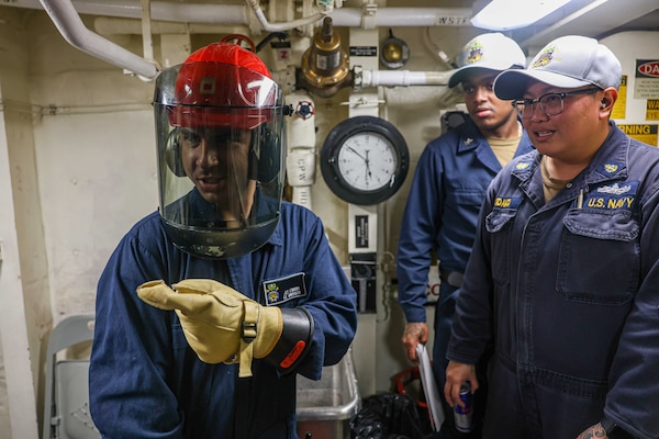 Sailors gather around some machinery.
