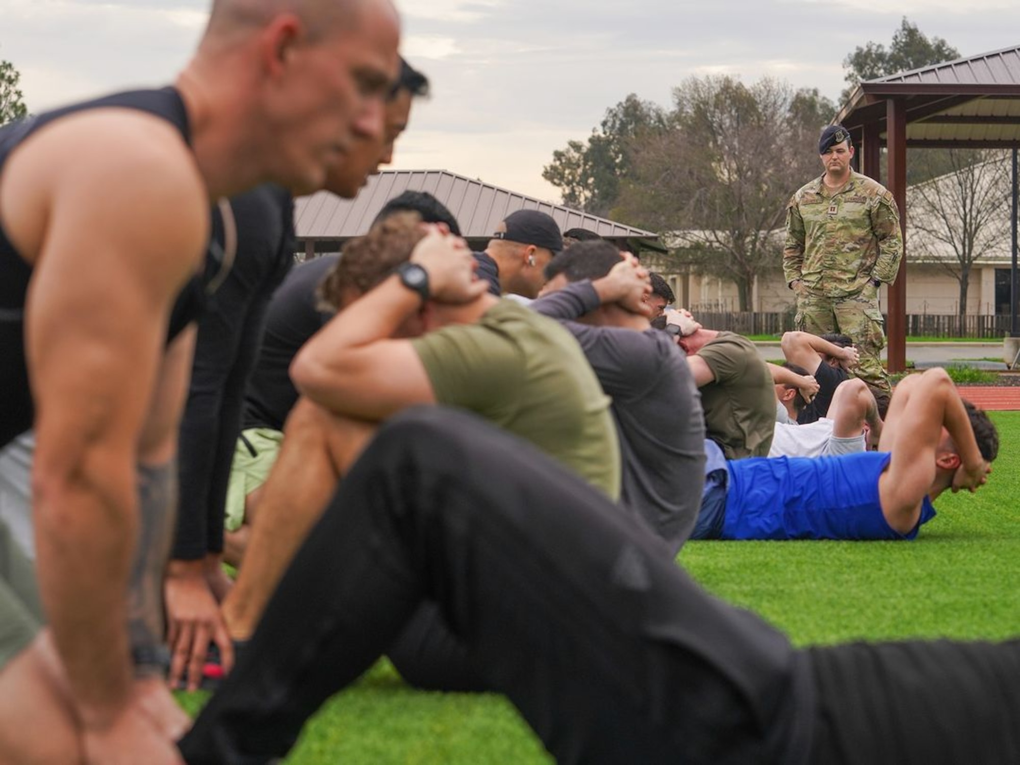 United States Air Force Airmen perform sit-ups while being scored by Capt. James Stocks, 9th Security Force operations officer, during the physical fitness qualification of the Tactical Response Team (TRT) tryouts Jan. 31, 2024, at Beale Air Force Base, California.