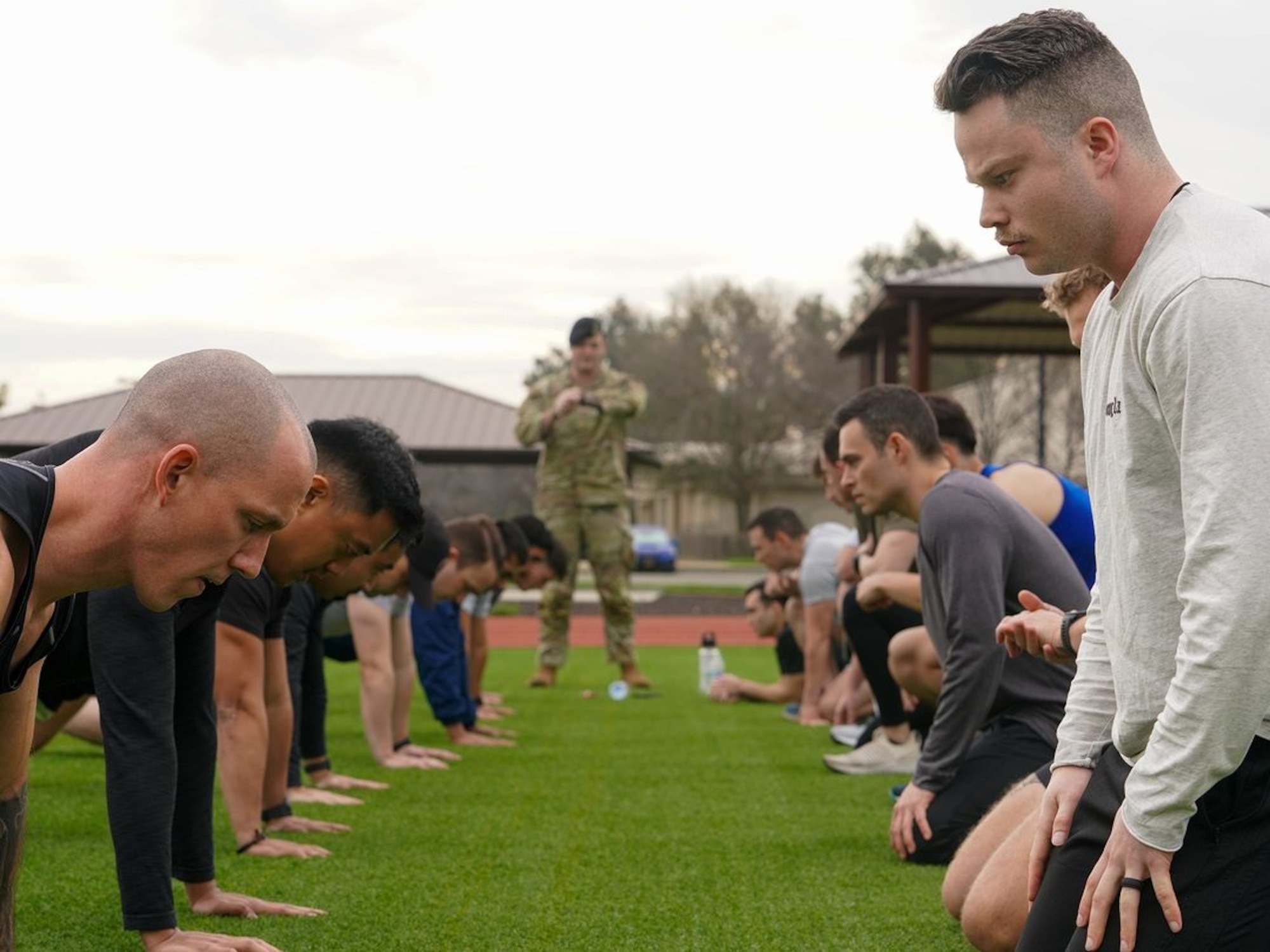 United States Air Force Airmen perform push-ups while being scored by Capt. James Stocks, 9th Security Force operations officer, during the physical fitness qualification of the Tactical Response Team (TRT) tryouts Jan. 31, 2024, at Beale Air Force Base, California.