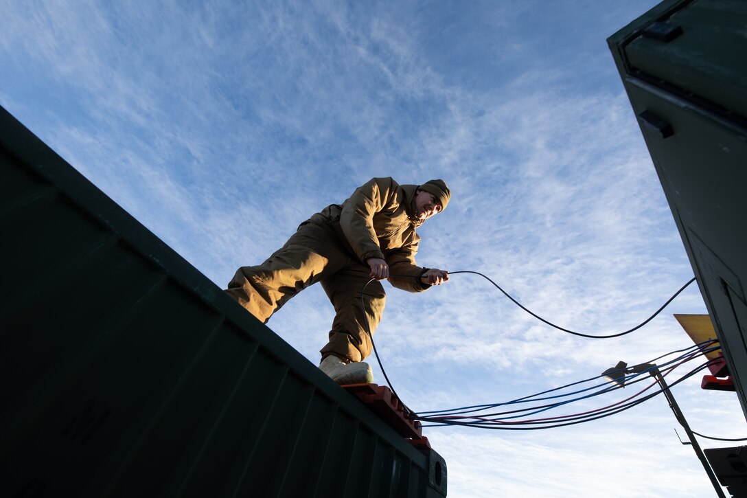 U.S. Marine Corps Cpl. Jacob Jonik, an aviation communication system technician with Marine Air Control Squadron (MACS) 24, Marine Air Control Group 48, 4th Marine Aircraft Wing, Marine Forces Reserve, lays down tactical fiber optic cable to interconnect the operational facility with a mobile Marine Aviation Operations Center (MAOC) at Fort Greely, Alaska, Feb. 10, 2024, in preparation for exercise ARCTIC EDGE 2024 (AE24). AE24 is a U.S. Northern Command-led homeland defense exercise demonstrating the U.S. Military's capabilities in extreme cold weather, joint force readiness, and U.S. military commitment to mutual strategic security interests in the Arctic region. (U.S. Marine Corps photo by Staff Sgt. Jestin Costa)