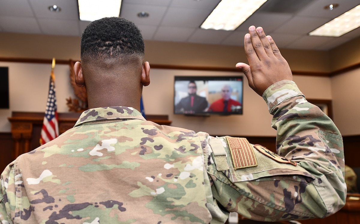 An airman raises his hand for the oath of citizenship