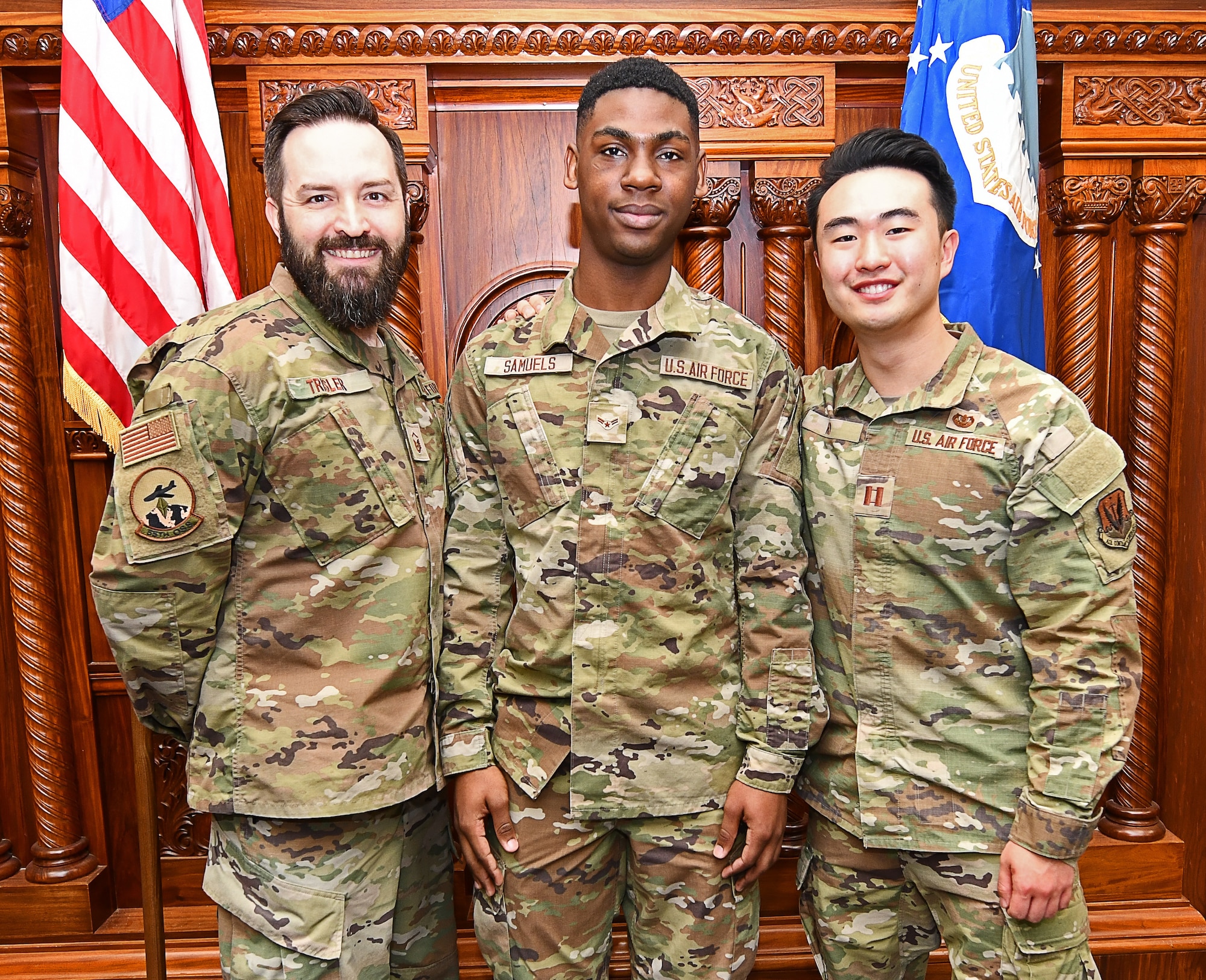 Three military members pose in a courtroom