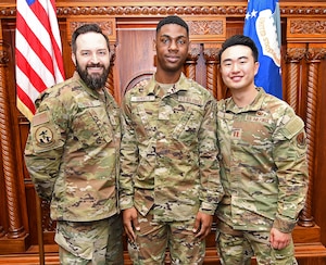 Three military members pose in a courtroom