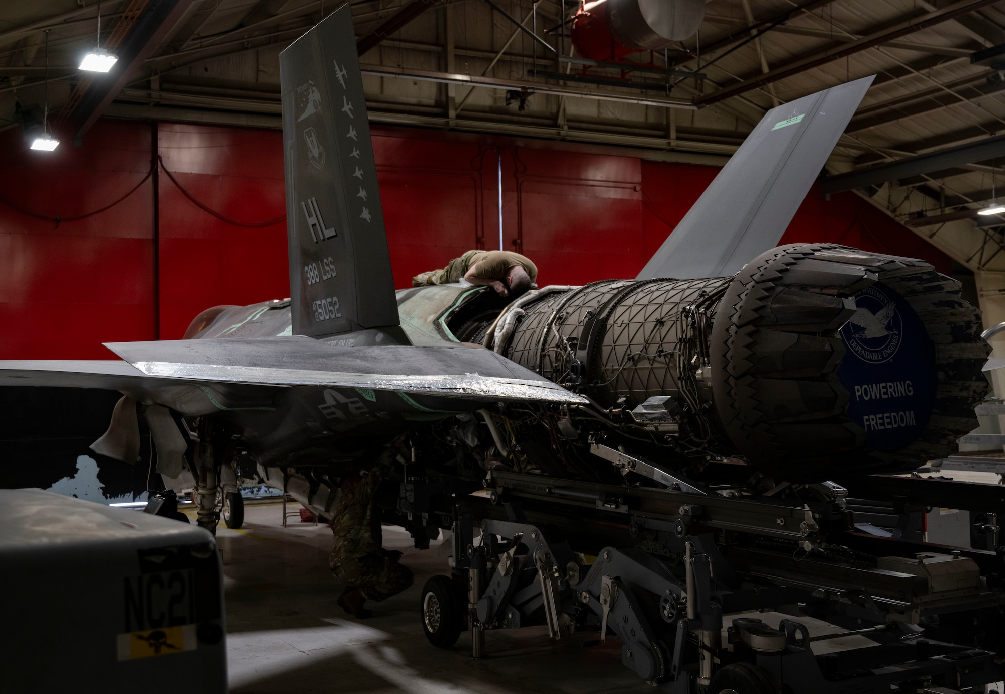 A photo of maintainers installing an engine into an F-35A Lightning II fighter jet.