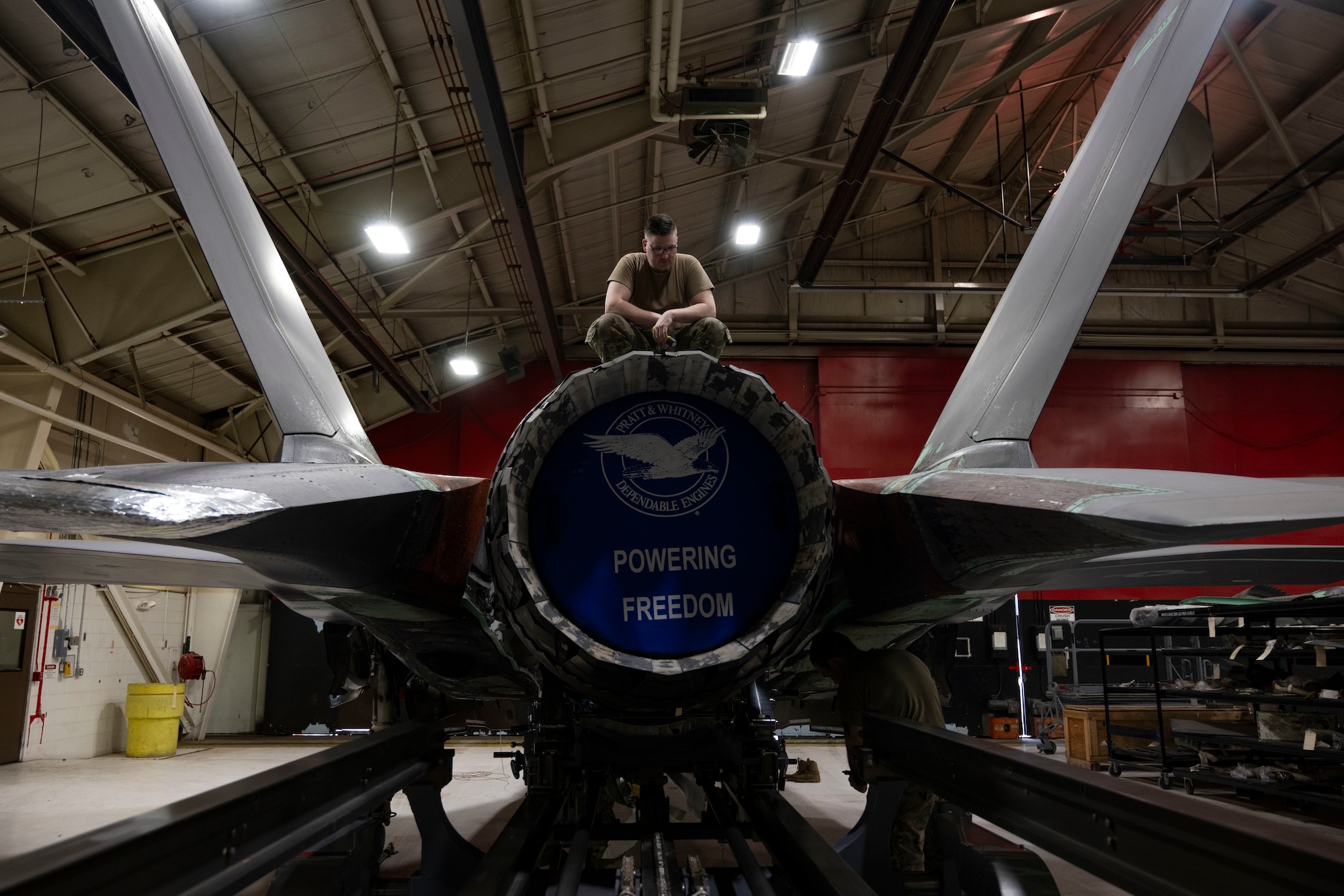 A photo of maintainers installing an engine into an F-35A Lightning II fighter jet.