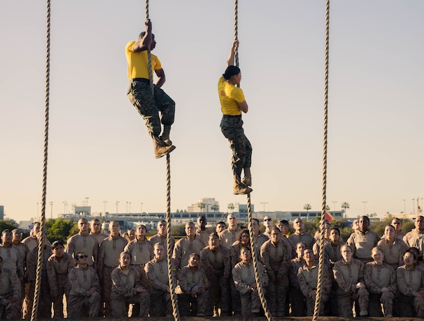 U.S. Marine Corps Drill Instructors Staff Sgt. Michael G. Williams, left, and Staff Sgt. Brenda E. Delosreyes, right, with Golf Company, 2nd Recruit Training Battalion, demonstrate how to properly climb the rope event during an obstacle course training event at Marine Corps Recruit Depot San Diego, California, Feb. 15, 2024. The O-Course includes obstacles recruits must overcome to enhance strength, agility, enhance, and confidence. (U.S. Marine Corps photo by Lance Cpl. Janell B. Alvarez)