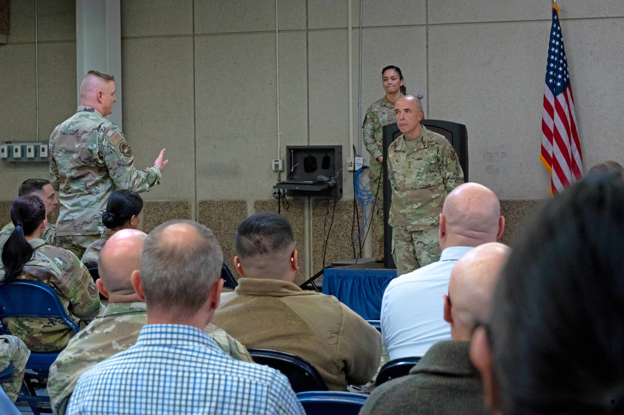 Lt. Gen. Miller stands at the front audience seated in during a town hall meeting.