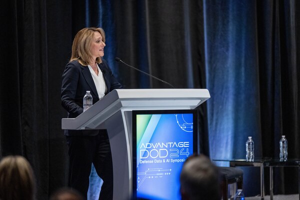 A civilian delivers remarks from behind a podium.
