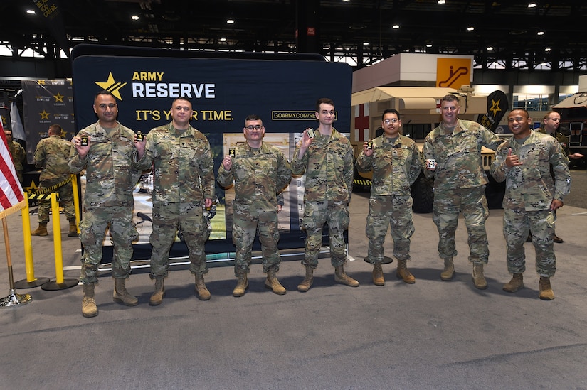 Army Reserve Soldiers, representing a variety of military occupational specialties, from a religious affairs specialist to an infantryman, pause for a photo after a re-enlistment ceremony with Brig. Gen. Geoffrey Norman, Director, Next Generation Combat Vehicle Cross Functional Team, at the Chicago Auto Show on February 13, 2024 at McCormick Place.