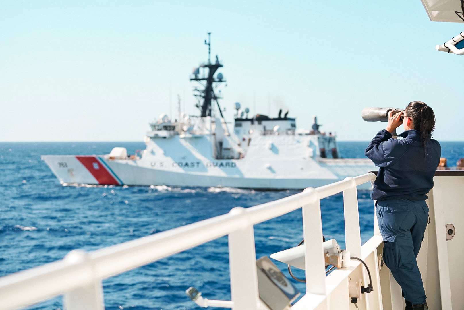 U.S. Coast Guard Seaman Vianey Salazar, a crewmember assigned to Coast Guard Cutter Thetis (WMEC 910), stands a lookout watch across from the Coast Guard Cutter Hamilton (WMSL 753), Jan. 11, 2024, in the Central Caribbean Sea. Thetis patrolled in support of the Coast Guard’s mission to combat illegal drug trafficking.