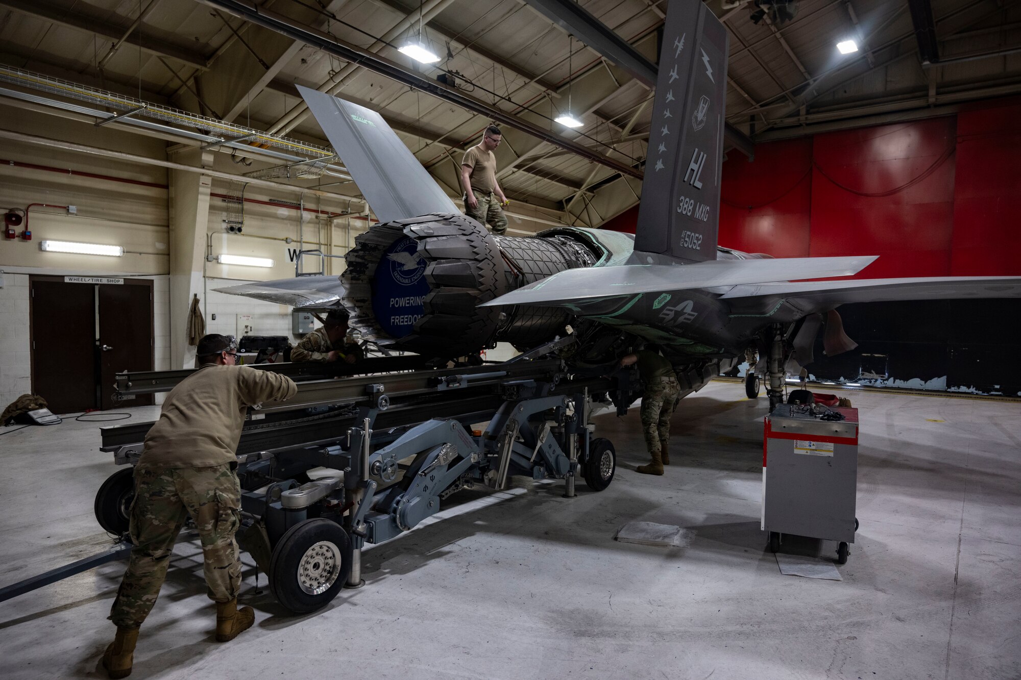 A photo of maintainers installing an engine into an F-35A Lightning II fighter jet.